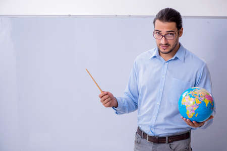 Young male geography teacher in front of whiteboard