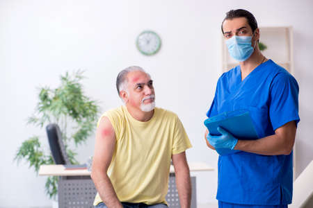 Injured old man visiting young male doctor traumatologist