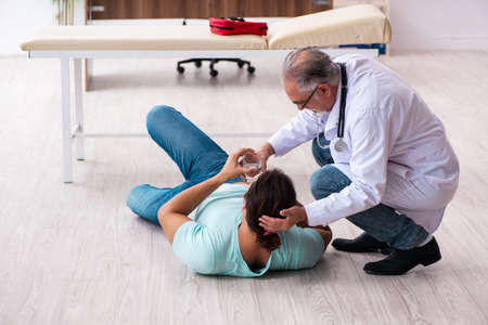 Old experienced doctor and young male patient lying on the floor