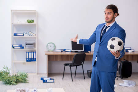 Young male employee playing football in the officeの写真素材