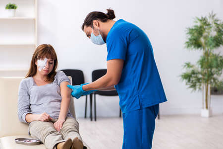 Young head injured woman visiting young male doctorの写真素材