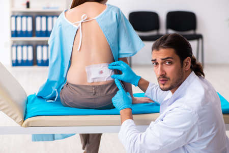 Injured young woman visiting young male doctorの写真素材