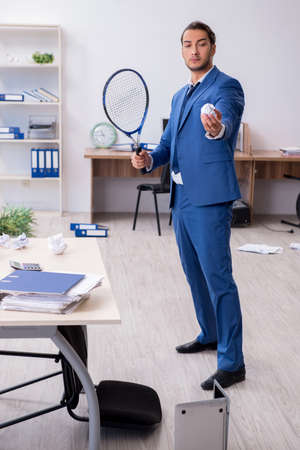 Young male employee playing tennis in the officeの写真素材