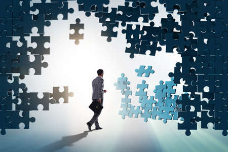 Businessman breaking wall of jigsaw puzzle
