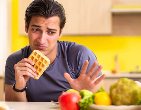 Man having hard choice between healthy and unhealthy foodの写真素材