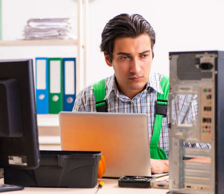 Young engineer repairing broken computer at the office