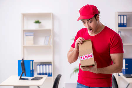 Young male courier delivering postbox to the officeの写真素材
