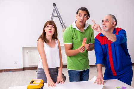 Young couple and old contractor in home renovation conceptの写真素材