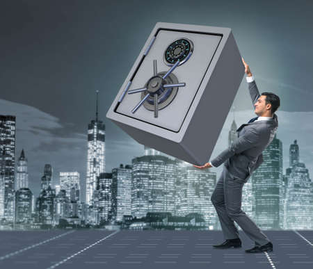 Businessman carrying metal safe in security conceptの写真素材