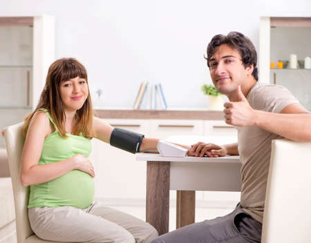 Husband checking pregnant wifes blood pressure