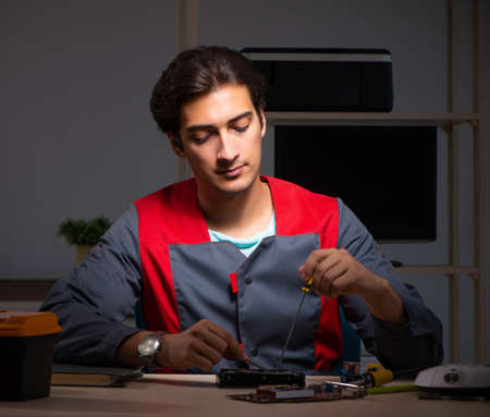 Young handsome repairman repairing computer