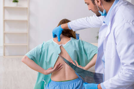 Young injured woman visiting male doctor chiropractor
