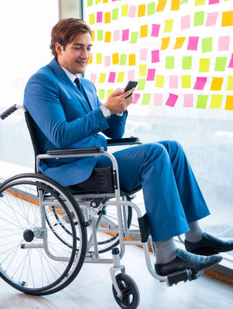 Young handsome man in wheelchair with many conflicting prioritieの写真素材