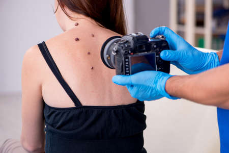 Young woman visiting male doctor dermatologistの写真素材