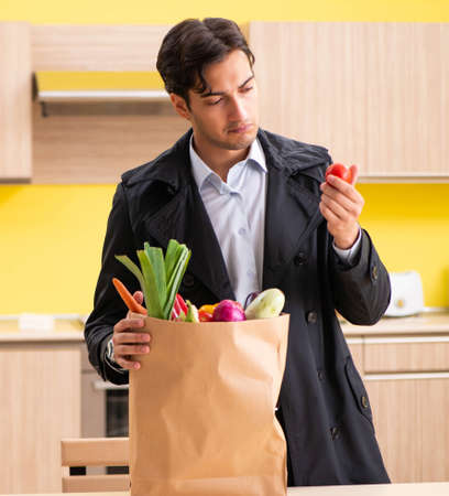 Young handsome man with vegetables in kitchenの写真素材