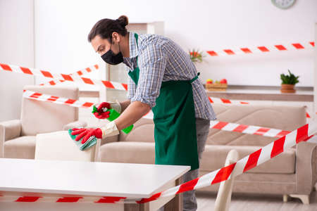 Young male sanitizer disinfecting indoors