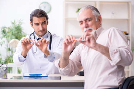 Young male doctor and old patient in antismoking conceptの写真素材