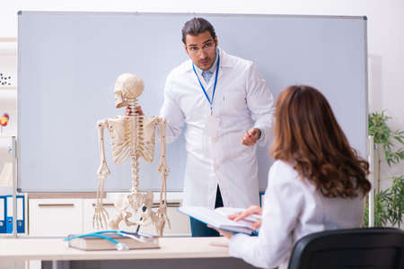 Young male teacher doctor, skeleton and female student in the clの写真素材