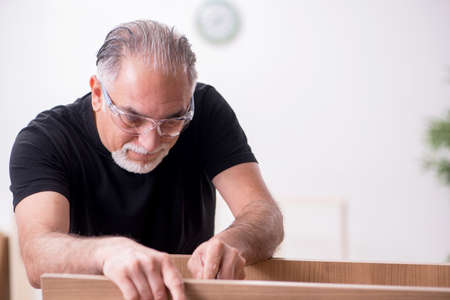 Old male carpenter working indoorsの写真素材