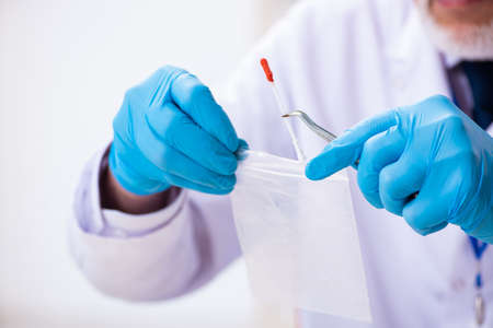 Old male expert criminologist working in the lab for evidenceの写真素材