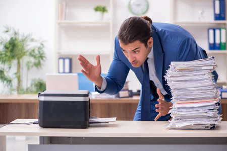 Young male employee making copies at copying machine