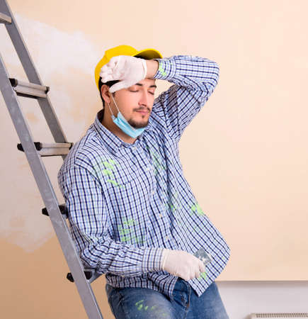 Young contractor sanding wall down with sandpaperの写真素材