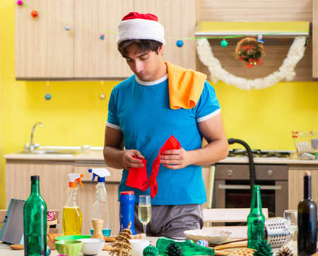 Young man cleaning kitchen after Christmas partyの写真素材