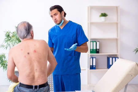Old man visiting young male doctor dermatologistの写真素材