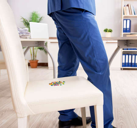 The office prank with sharp thumbtacks on chairの写真素材