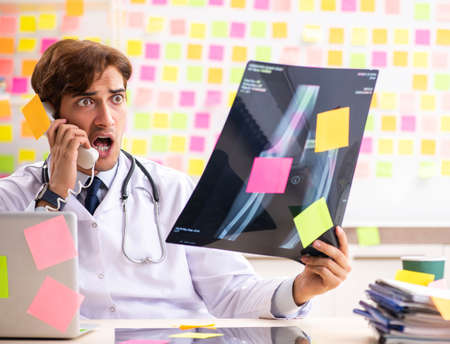 Male doctor with many conflicting priorititesの写真素材