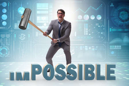 Businessman hitting the word impossible with hammer