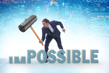 Businessman hitting the word impossible with hammer