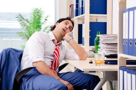 Young businessman employee drinking in the officeの写真素材