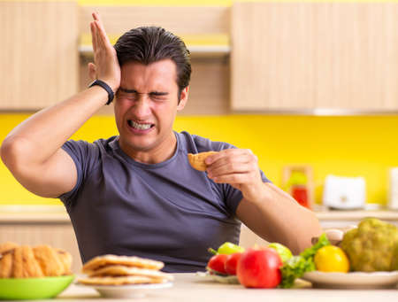 Man having hard choice between healthy and unhealthy foodの写真素材