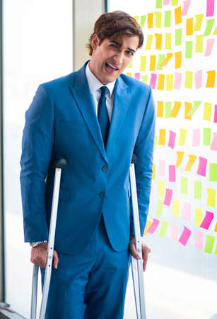 Young handsome man with crutches in conflicting priorities conceの写真素材