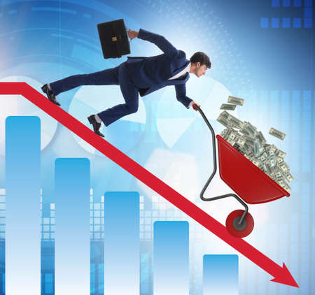 Businessman pushing money wheelbarrow down the chartの写真素材