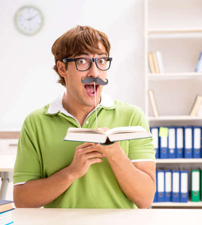 Student with fake moustache reading bookの写真素材