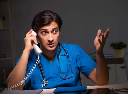 Young handsome doctor working night shift in hospitalの写真素材