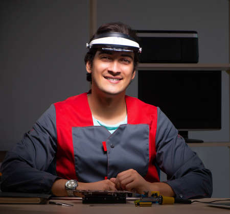 Young handsome repairman repairing computer