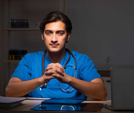 Young handsome doctor working night shift in hospitalの写真素材