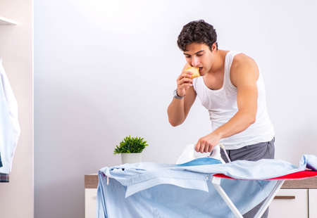 Young man ironing in the bedroomの写真素材
