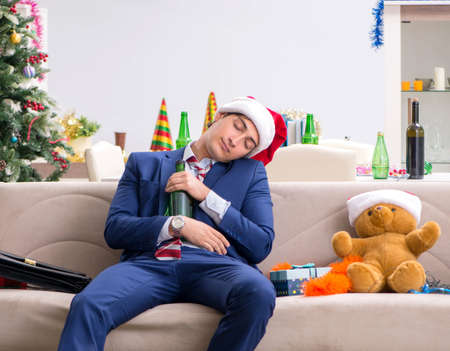 Young handsome employee celebrating Christmas at workplaceの写真素材