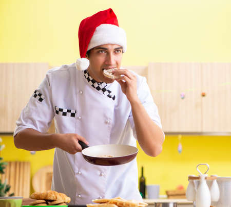 Young chef husband working in kitchen at Christmas eve