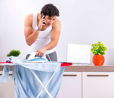 Young man ironing in the bedroomの写真素材
