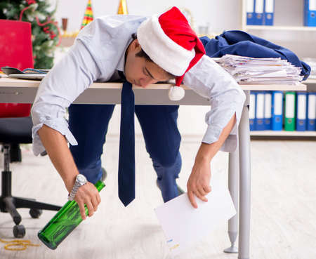Young handsome employee celebrating Christmas at workplaceの写真素材