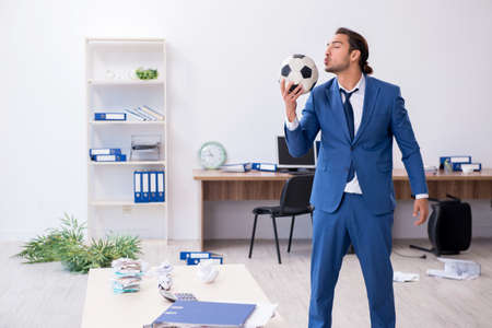 Young male employee playing football in the officeの写真素材