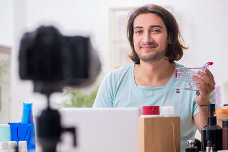 Young male shopaholic recording video for his blogの写真素材