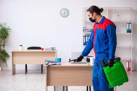 Young male contractor disinfecting officeの写真素材