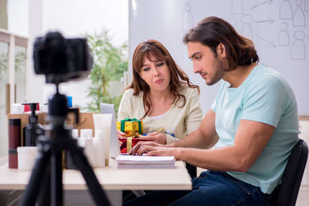 Young couple sales consultants recording video for their blogの写真素材