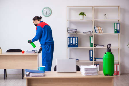 Young male contractor disinfecting officeの写真素材